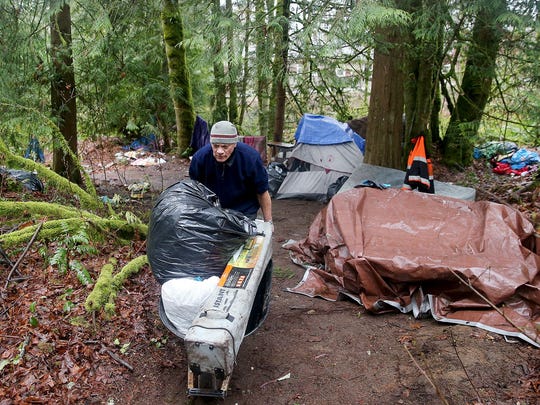 Resident of a homeless camp uses wheelbarrow to clean-up encampment