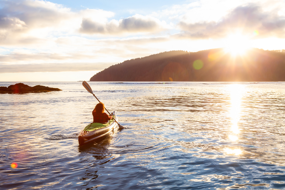 Kayaker paddles towards the setting sun